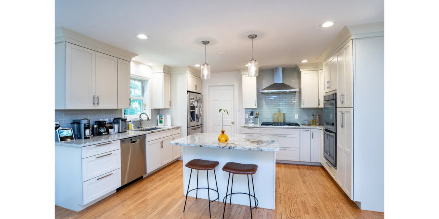a kitchen with white cabinets and wooden floors