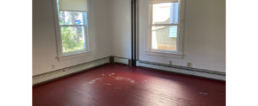 an empty room with two windows and a hard wood floor