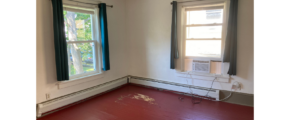 an empty room with a red floor and two windows