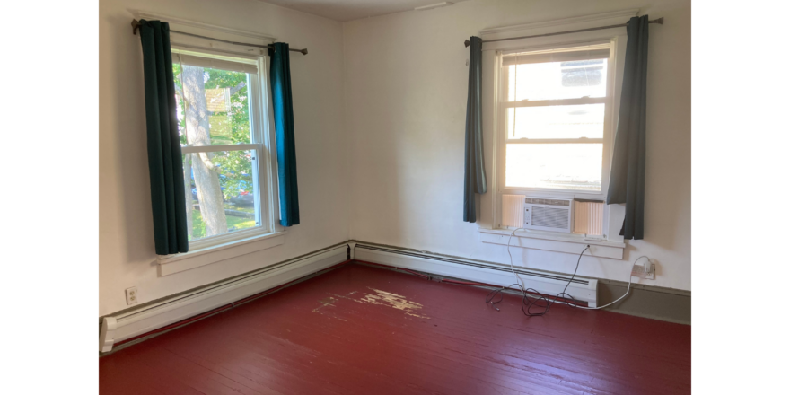 an empty room with a red floor and two windows