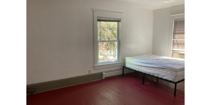 an empty room with a bed and a window
