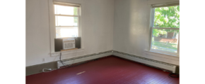 an empty room with a red floor and a window