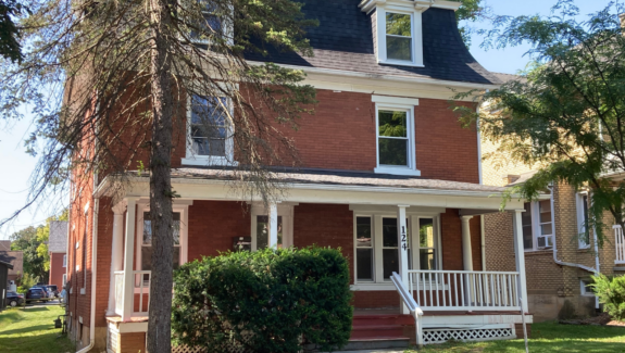 a red brick house with a white porch