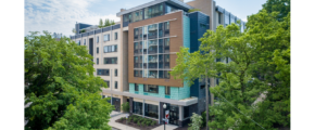 a large multi-faceted building with many windows and a lot of trees in front of it
