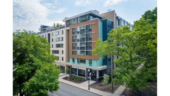 a large multi-faceted building with many windows and a lot of trees in front of it