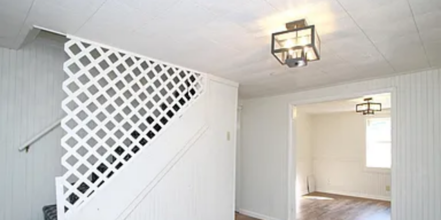 an empty room with a stair case and light fixture