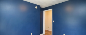 an empty room with blue walls and wood floors