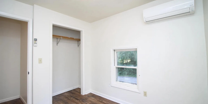 an empty room with wood floors and a window