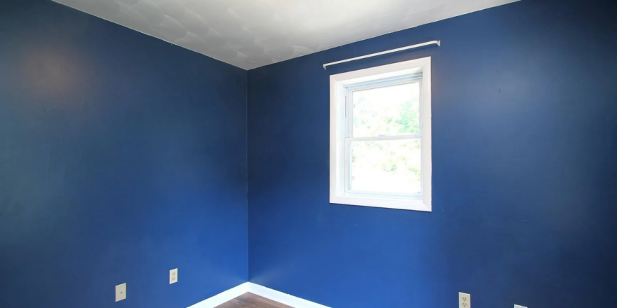 an empty room with blue walls and a window