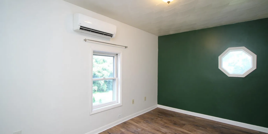 an empty room with a wood floor and green walls