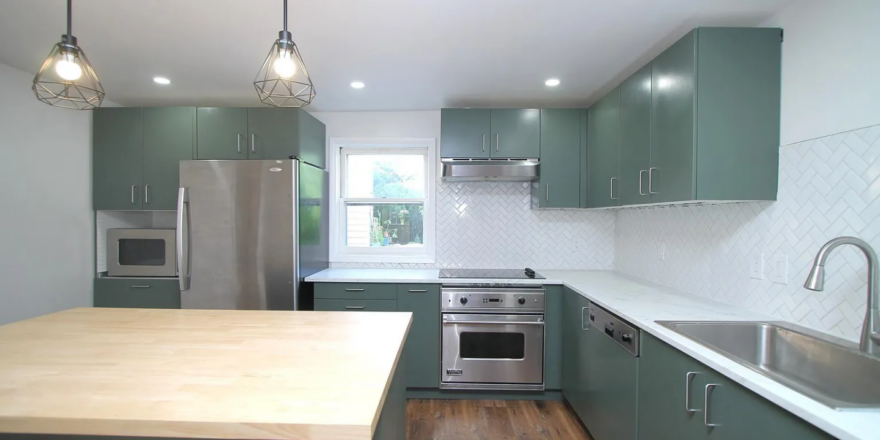 a kitchen with green cabinets and stainless steel appliances