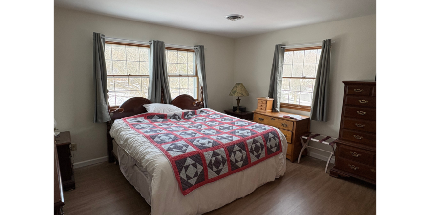 a bed sitting in a bedroom next to two windows