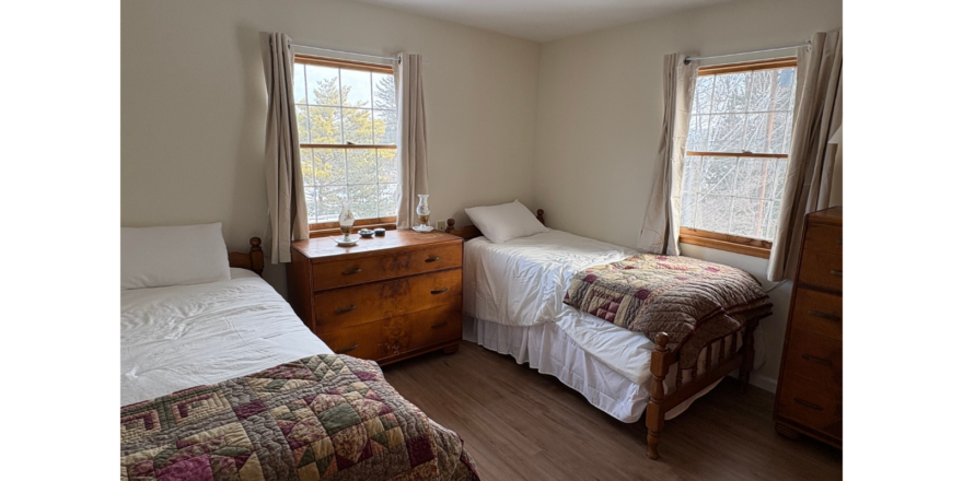 a bedroom with two beds and two windows