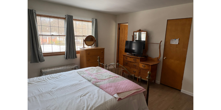 a bedroom with a bed, dresser and television