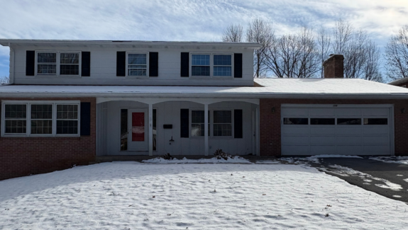 a house with snow on the ground in front of it