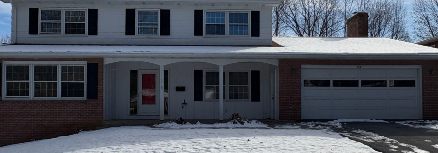 a house with snow on the ground in front of it