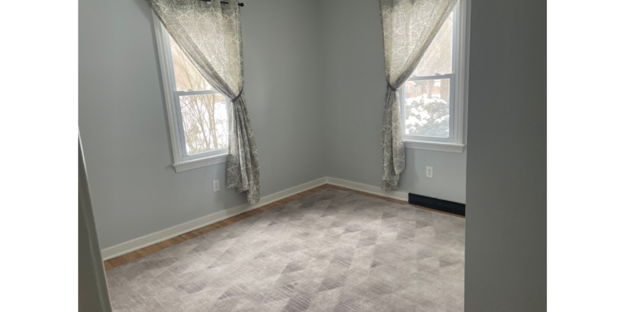 a empty room with two windows and a carpeted floor