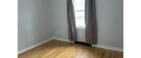 an empty room with a window and a wooden floor