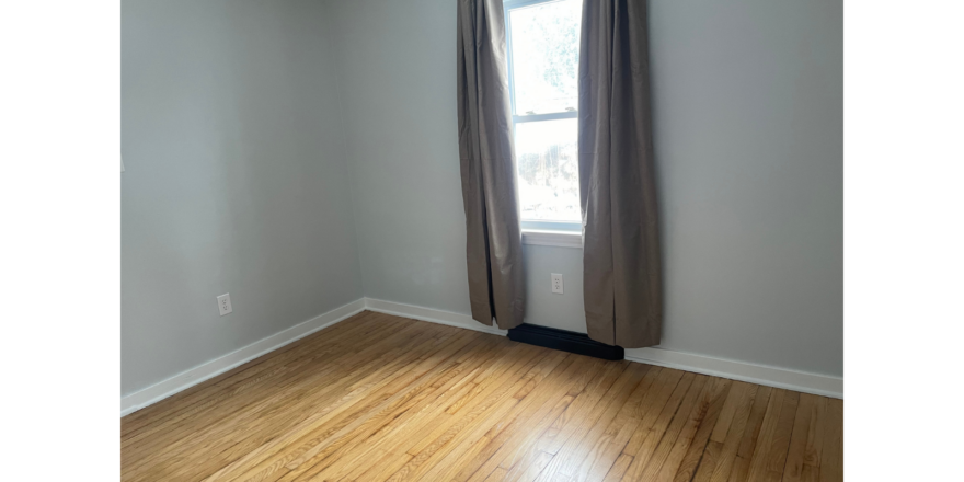 an empty room with a window and a wooden floor