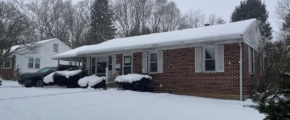 a house covered in snow with cars parked in front of it