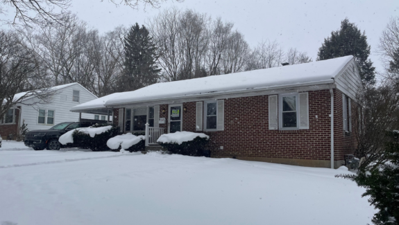 a house covered in snow with cars parked in front of it