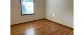 an empty room with wood floors and a window