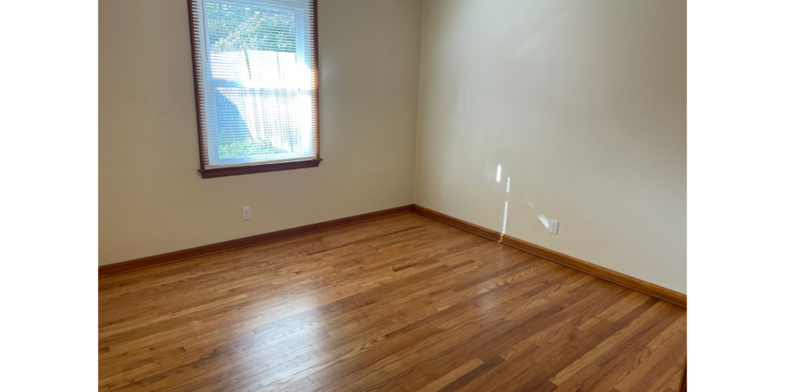 an empty room with wood floors and a window