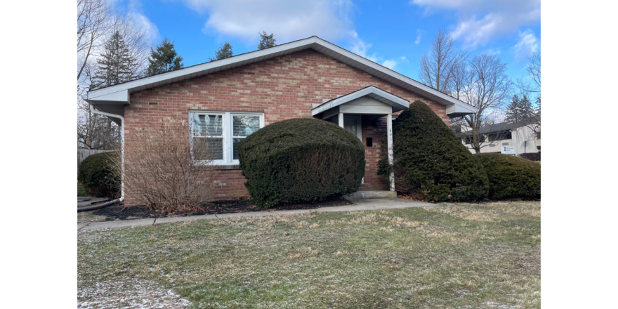 a brick house with two bushes in front of it