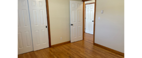 an empty room with two doors and a hard wood floor