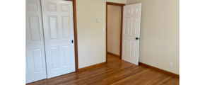 an empty room with two doors and a hard wood floor