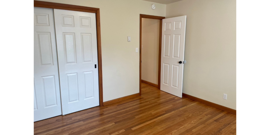 an empty room with two doors and a hard wood floor