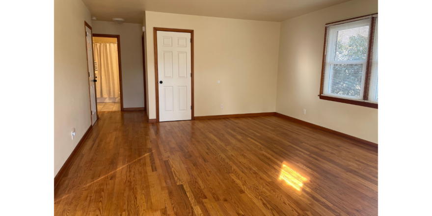 an empty room with wood floors and a door