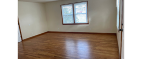 an empty room with wood floors and a window