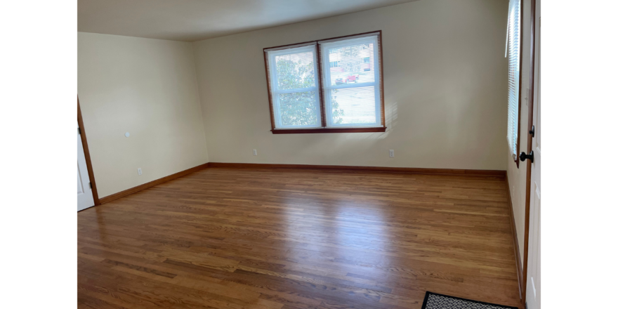 an empty room with wood floors and a window