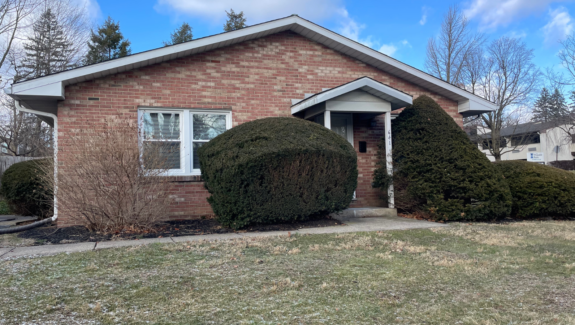 a brick house with two bushes in front of it