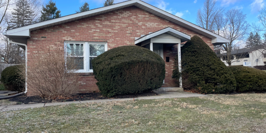 a brick house with two bushes in front of it