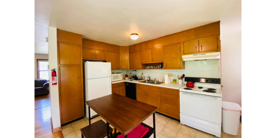 a kitchen with a table, stove, and refrigerator