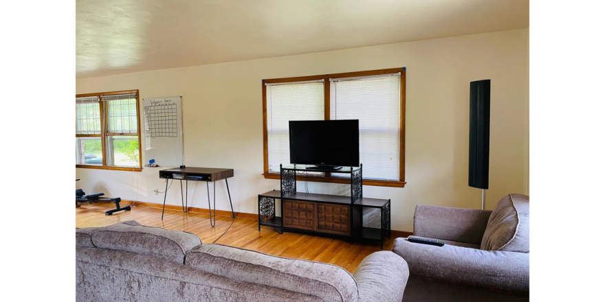a living room with a couch, television, and windows