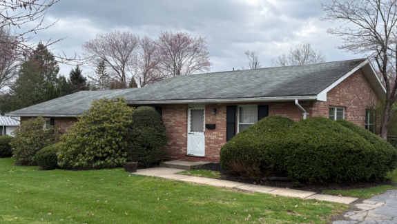 a brick house with green grass and trees