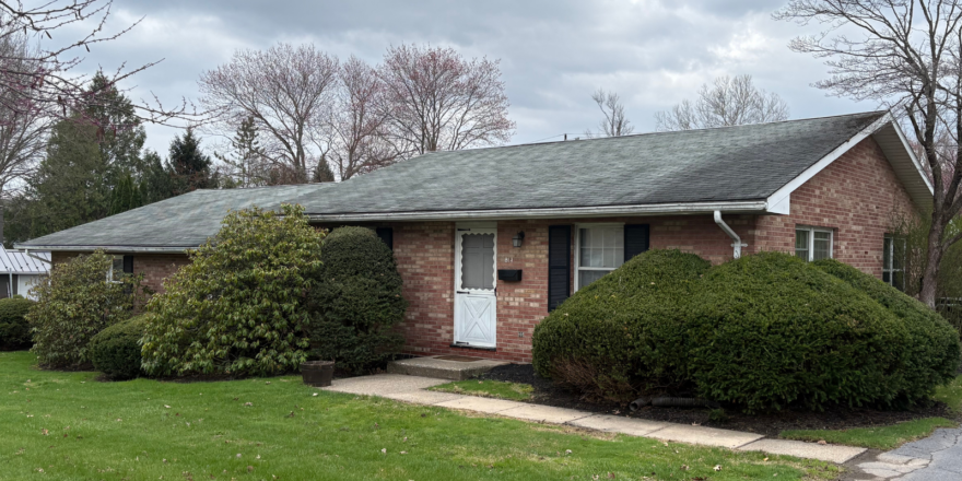a brick house with green grass and trees