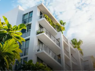 a tall white building with balconies and plants on the balconies