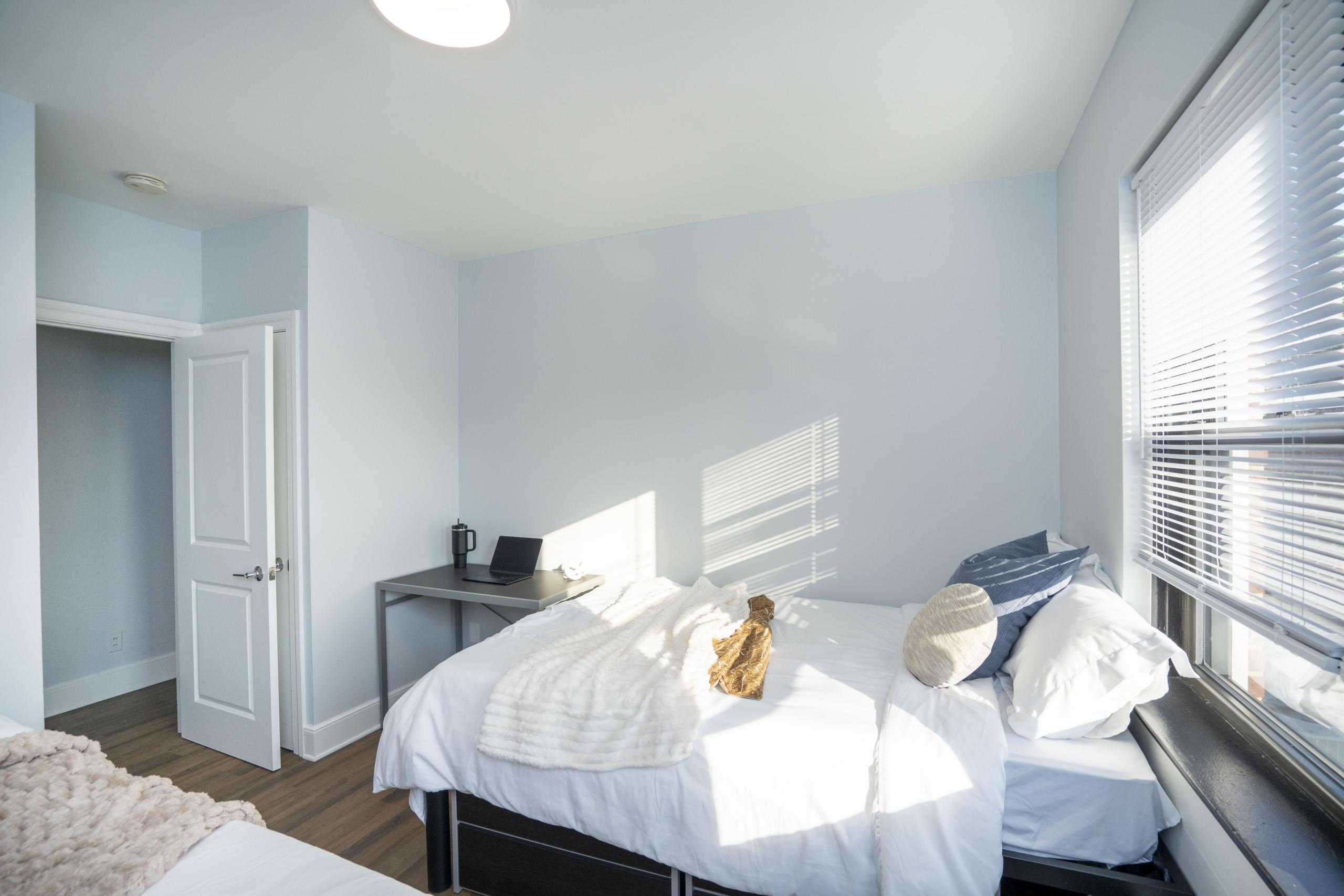 a bed room with a neatly made bed and a flat screen tv