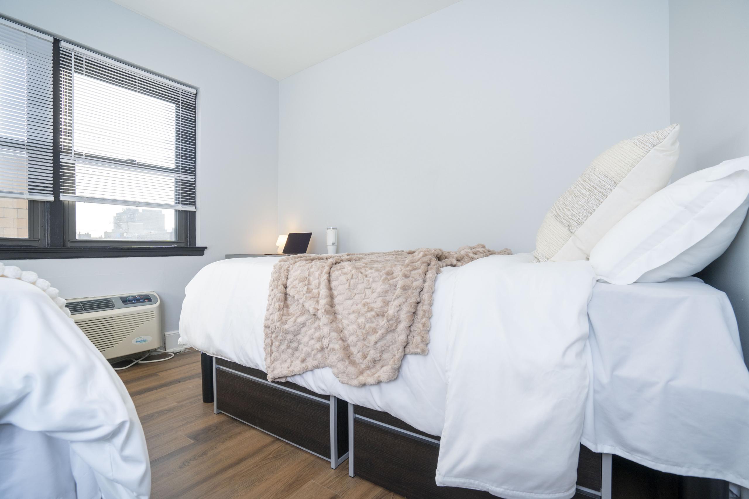 a bed room with a neatly made bed and a window