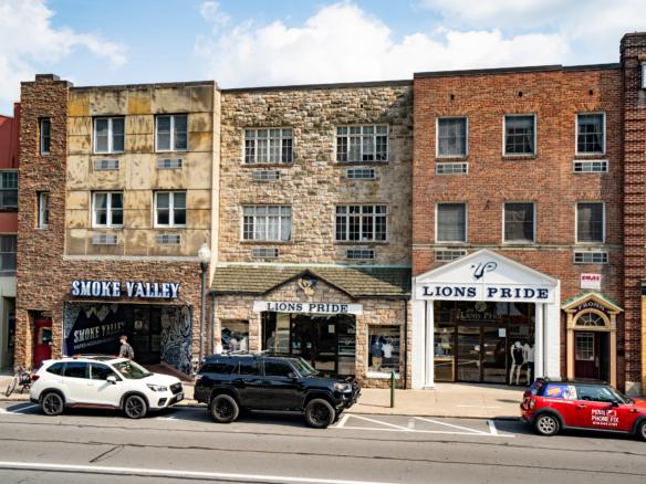 cars parked on the side of the road in front of a row of buildings