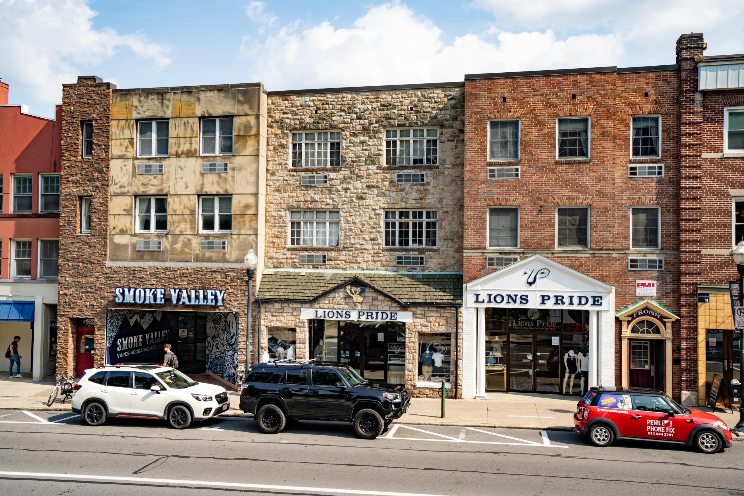 cars parked on the side of the road in front of a row of buildings