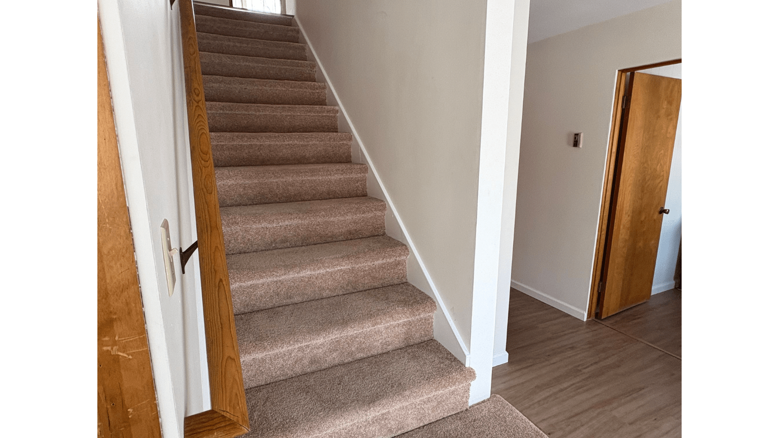 Interior stairs leading to upper floor, beige carpet, white walls