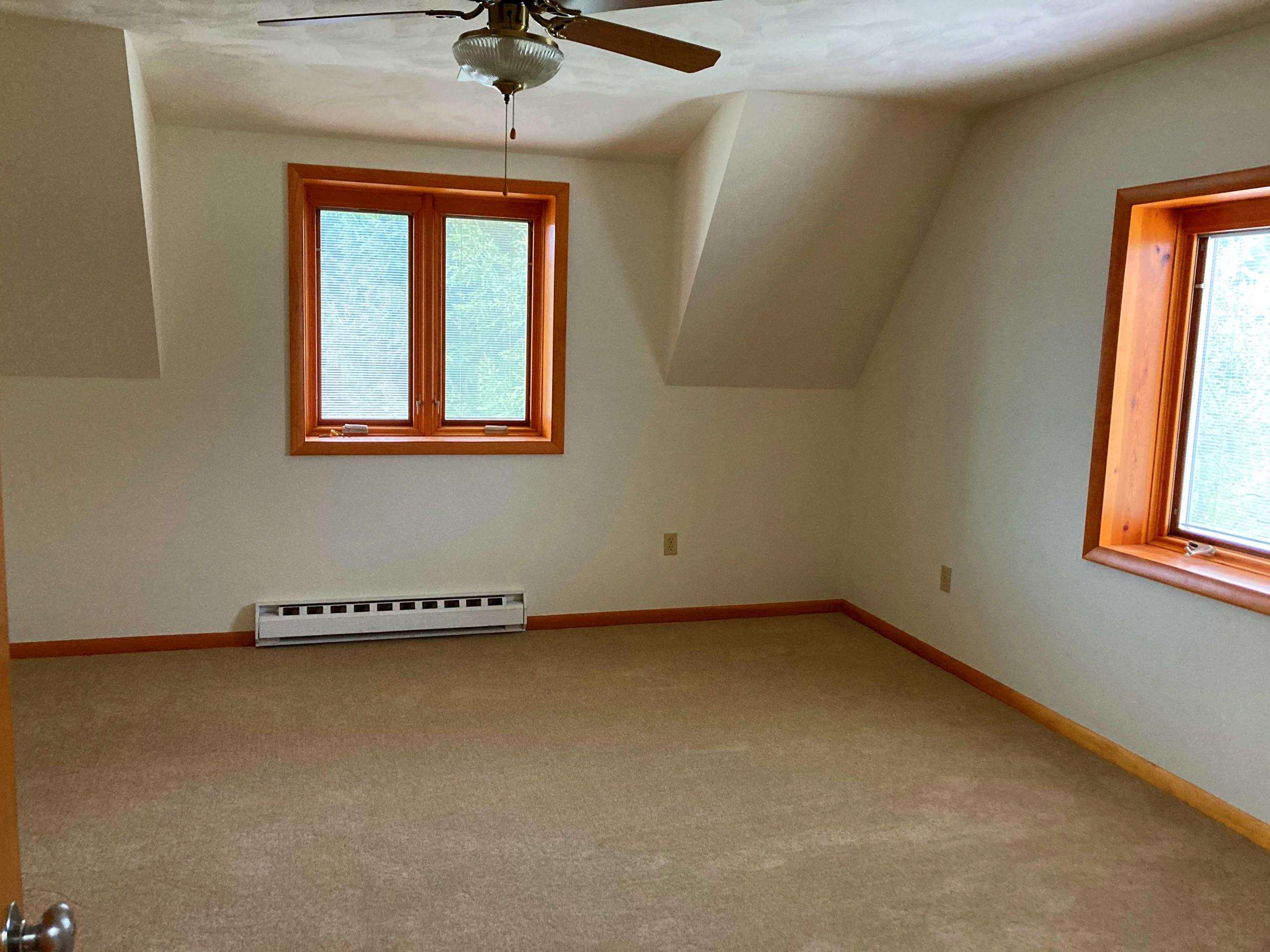 Empty bedroom with tan carpet and windows