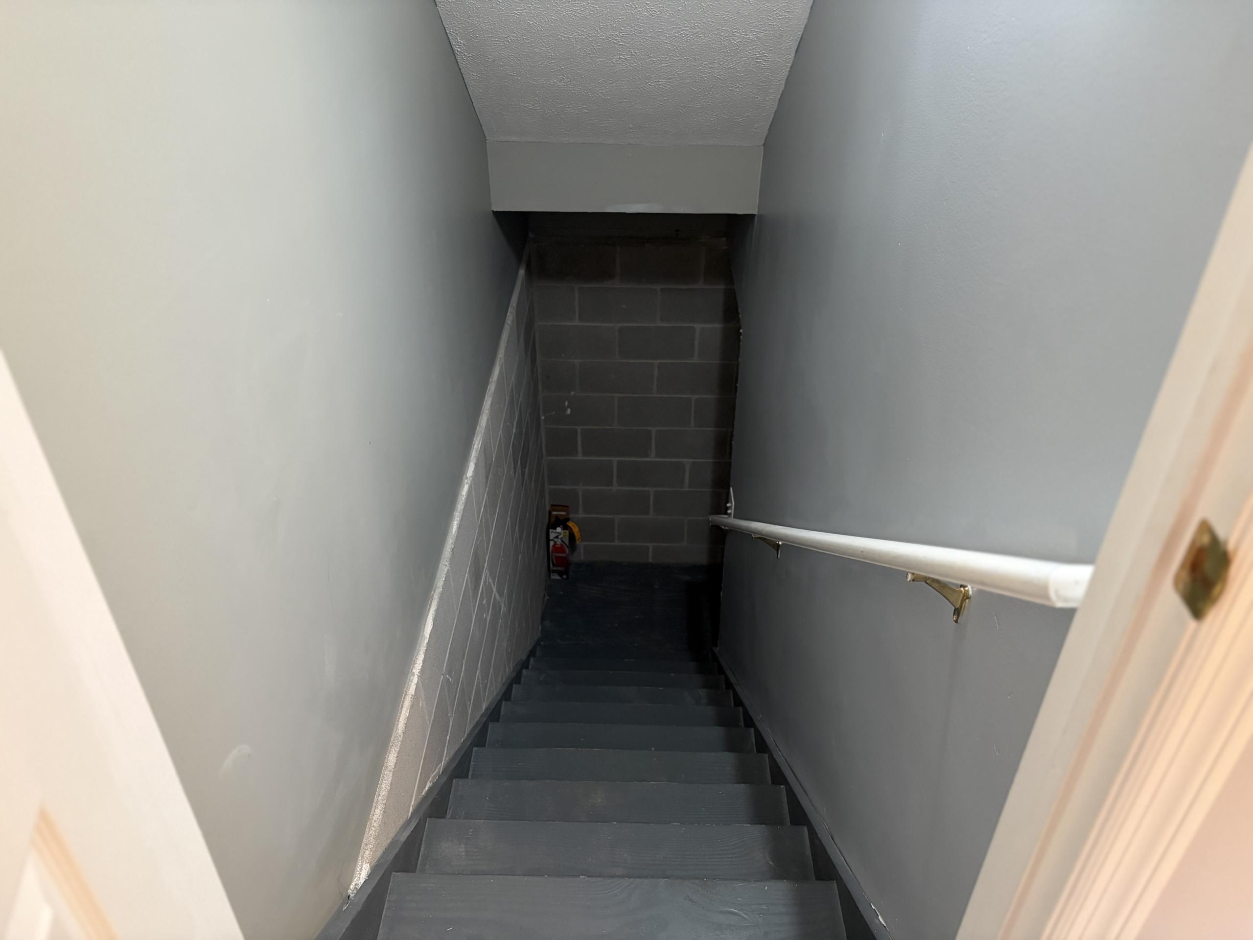 Stairway to basement with cinder block wall