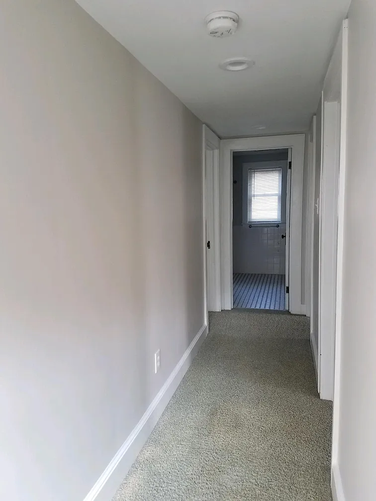 Hallway leading to bathroom with tiled floor.