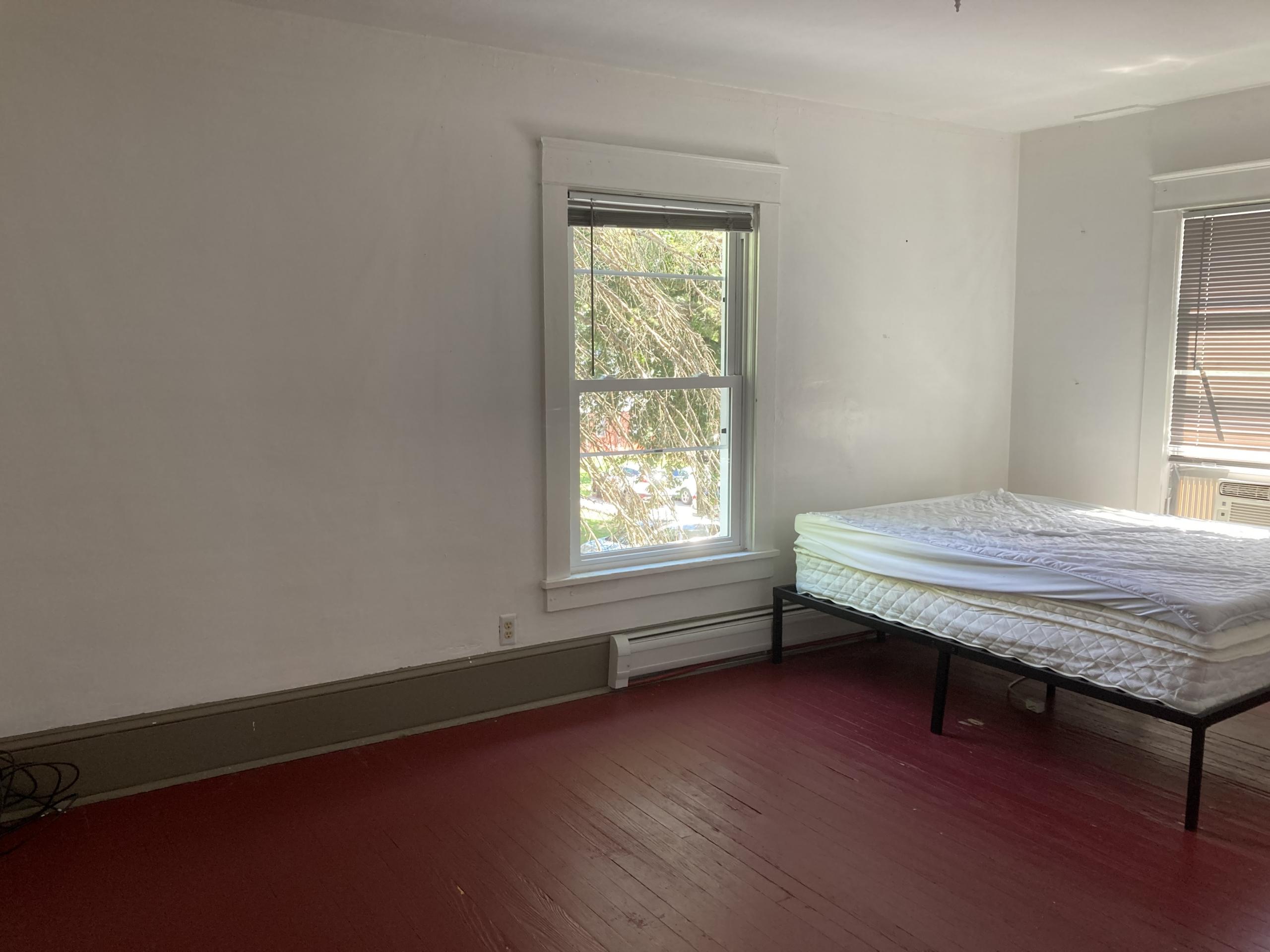 Bed in empty room with red floor